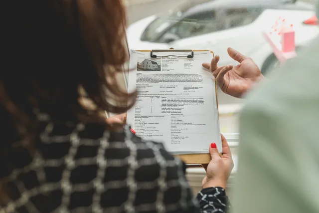 Real estate agent reviewing property documents with a client. Acquisitions and exits: reading deal mechanics